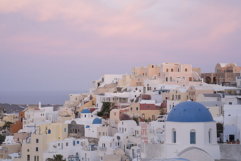 Colourful houses of Oia at dawn beneath a pink sky