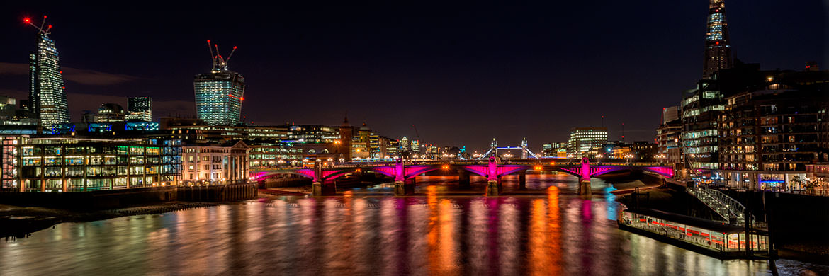 City of London skyline featuring Southwark Bridge lit in red at night