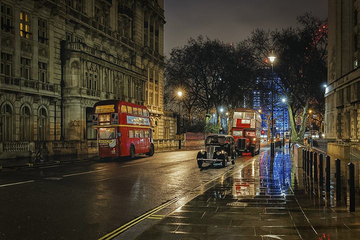 Two buses and a taxi on a wet night in London