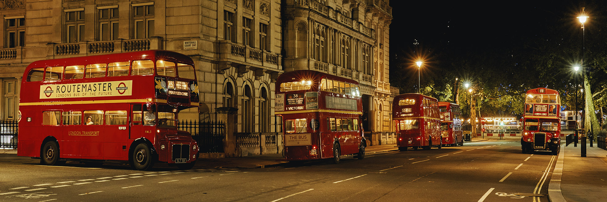Photograph of five vintage London buses at night